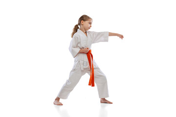 Studio shot of little girl, young karate training alone isolated over white background. Concept of sport, education, skills