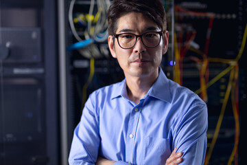 Portrait of asian male engineer with arms crossed in computer server room