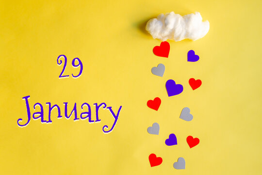 29 january day of month, colorful hearts rain from a white cotton cloud on a yellow background. Valentine's day, love and wedding concept