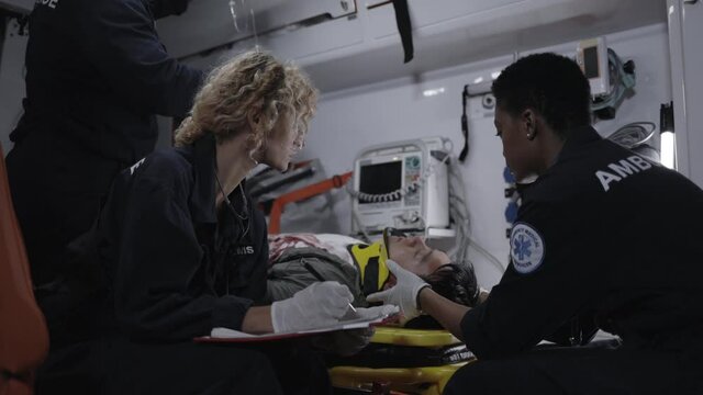 Paramedics riding in ambulance car with patient on stretcher
