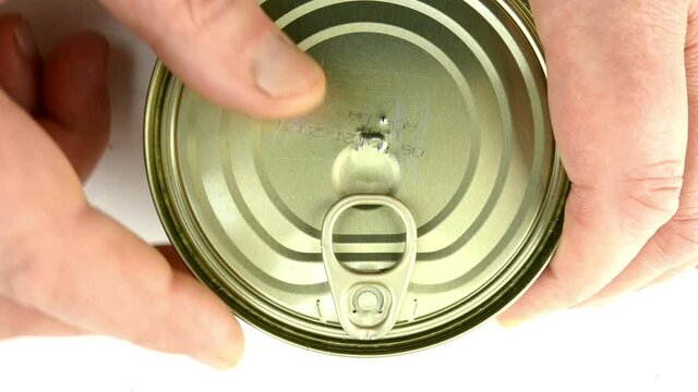 Hand opens metallic tin can stewed meat. Lifts the metal cover. Fast canned food concept. Top view.