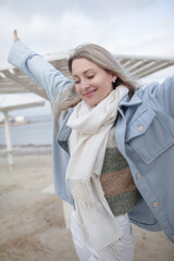 Beautiful woman dressed woolen blue jacket, white scarf and trousers walking in the beach, reston and enjoy the time is in with you, against the shore of the beach at background sea and sky