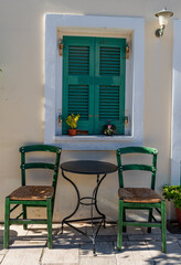 Fototapeta na wymiar A table with two chairs by the window of a Greek village house.
