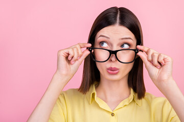 Photo of young pretty girl curious interested look empty space hands touch eyeglasses isolated over pink color background