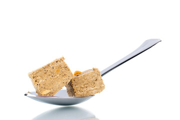Two pieces of halva with peanuts with a metal spoon, close-up, isolated on white.