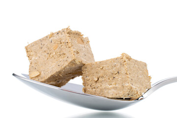 Two pieces of halva with peanuts with a metal spoon, close-up, isolated on white.