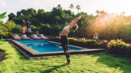 Flexible woman doing yoga near swimming pool