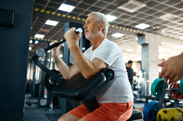 Fototapeta na wymiar Elderly man, workout on exercise machine in gym