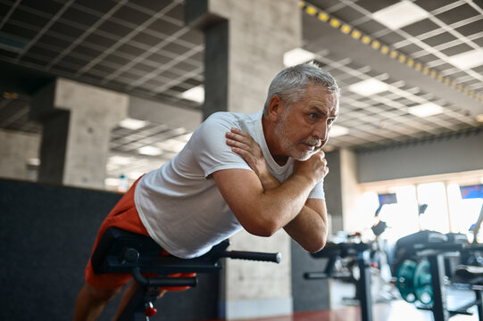 Elderly man in sportswear doing abs exercise, gym