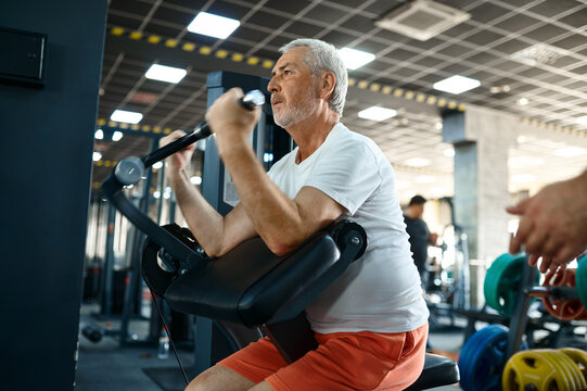 Elderly man, workout on exercise machine in gym