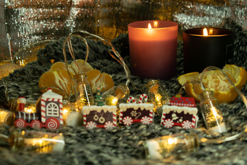 Christmas still life with a gingerbread train, a garland in the form of jars with a Christmas tree and snow. The still life is located on a knitted scarf, which gives the photo an atmosphere