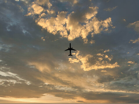 Looking up at jet airliner in front of pretty clouds