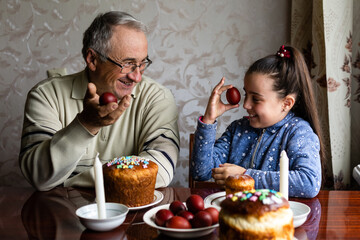 Family Decorating Easter Eggs On Table, grandfather and granddaughter.