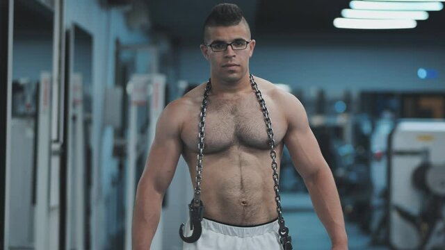 Muscular Arab in the gym walks with a metal chain after a workout.