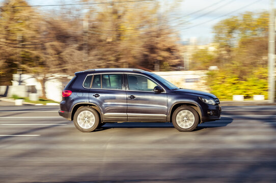 Volkswagen Tiguan first generation 5N Car driving on city street. Dark blue VW Tiguan SUV moving on the road with blurred autumn background