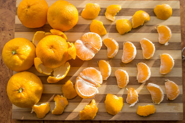 Tangerines and mandarin slices on wooden planks top view.