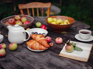 beautiful autumn still life in apple orchard, old table with cup, teapot, apples and book. Fall Getaway, Apple Picking anf Harvest Day Celebration concept