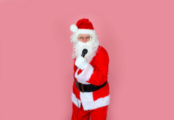 Funny vocalist shouting into the microphone, wearing a fur coat, gloves, isolated bright background. Santa Claus sings into the microphone