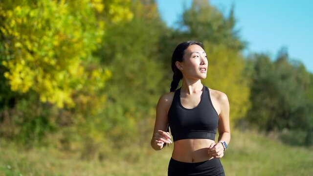 Young asian happy woman runner jogging in forest or city park. Morning jog. Active healthy lifestyle. attractive fitness female. Sport workout outdoor. Athlete training run exercise in the fresh air