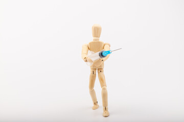 wooden mannequin with syringe against white background