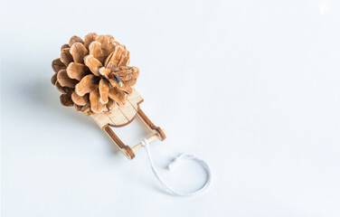 A toy sleigh brought a pine cone. Eco-friendly simple gift on a white background concept. Top view.