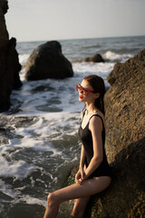 woman in swimsuit sunglasses ocean rocks posing