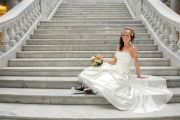 contemporary bride sitting on staircase holding bouquet and smiling