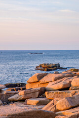 The pink granite slabs of granite along the Maine coast glow in the new morning sunrise light