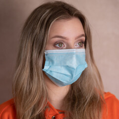 Sad young woman wears mask to protecr herself and others against COVID infection