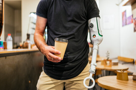 Crop man with artificial limb with cup of coffee