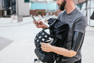 Anonymous man with artificial arm browsing smartphone