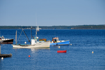 Fototapeta na wymiar Anchored colorful red white and blue Lobster Boats on a perfect summer day sitting at harbor