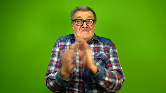 Mature adult strange man in stupid glasses is emotionally claps his hands and and nods his head approvingly. Green screen.