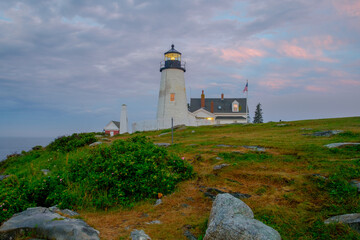 Fototapeta na wymiar Pink dawn light on the beautiful Pemaquid Lighthouse with the orange sunrise reflected in the lighthouse windows