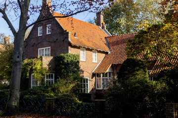 Large Dutch brick exterior facade of stately home surrounded by autumn colors against a clear blue sky. Real estate and housing market concept in The Netherlands.