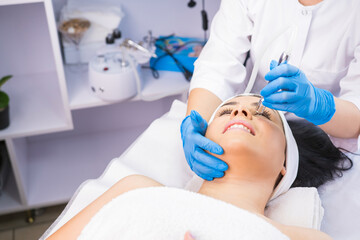 Woman in the beauty salon undergoes a facial microdermabrasion rejuvenation procedures, professional cosmetologist doing her work.