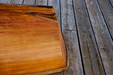 Hand crafted wooden rowboat stern laying on a deck upside down at dusk