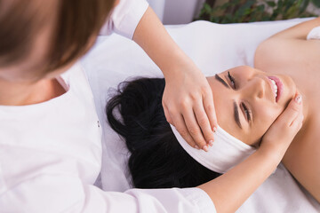 Obraz na płótnie Canvas Young woman came to a professional specialist masseur in the clinic to sets her cervical spine, facial massage, health body care concept. 