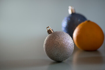 Silver and blue Christmas tree toys with tangerine against mint background