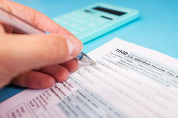  female hand fills out tax forms 1040