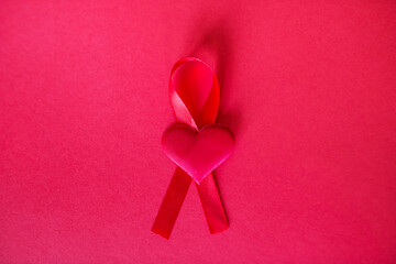 Fototapeta premium Top view of red ribbon and small red heart, cancer awareness symbol,