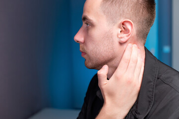 Obraz premium Close-up of a man holding his neck with his hand. Neck pain and self-massage