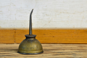 An old Brass oil can sits on a workbench used in a boat builders workshop