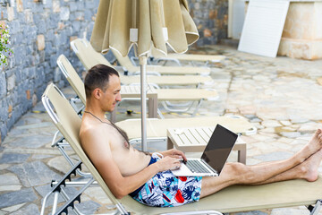 man using a laptop near the pool