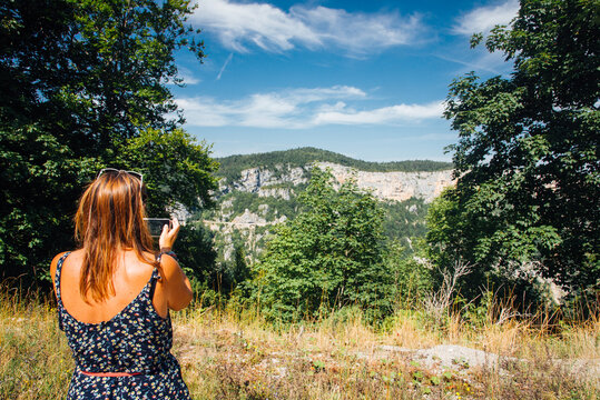 Une femme photographiant une montagne. Une femme touriste dans le Vercors. Une femme prend des photos dans la nature.
