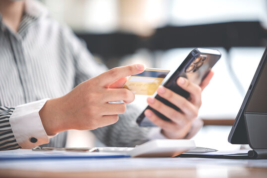 female hand holding phone and credit card