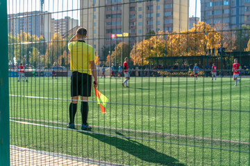 Football referee watching the course of the game on a green soccer floor during a match in the...