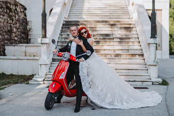 Happy newlywed couple posing with a red bike for their wedding photoshoot
