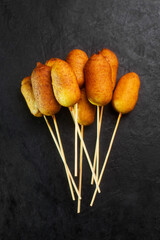 Corn dogs cooked with sausage and dough, black background top view - obrazy, fototapety, plakaty