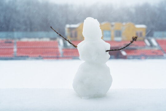 Snowman on the background of a snow-covered stadium